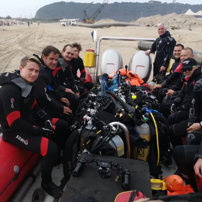 Groupe de plongeurs équipés sur un bateau pneumatique sur une plage