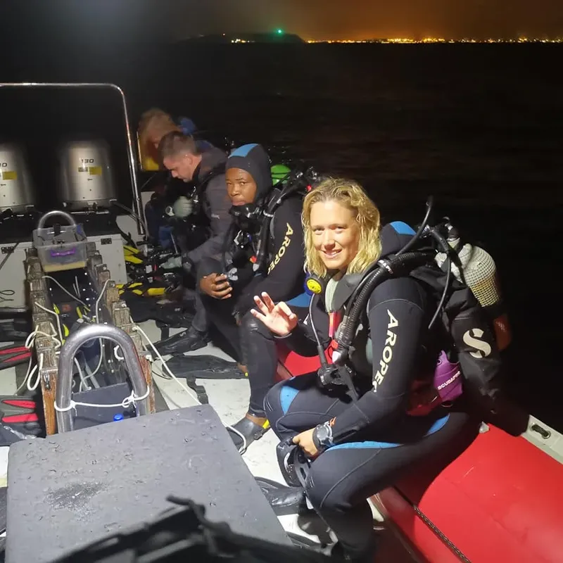 Plongeurs souriants à bord d'un bateau, équipés et prêts à plonger