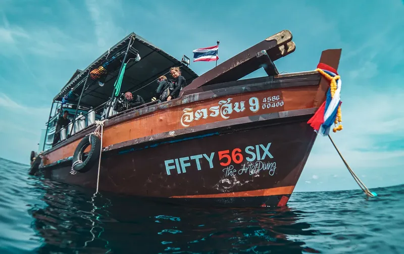 Bateau de plongée traditionnel avec des plongeurs et des drapeaux thaïlandais