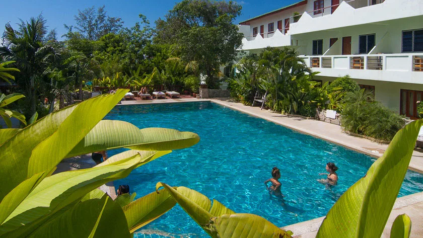 Piscine d'un centre avec des baigneurs et végétation tropicale