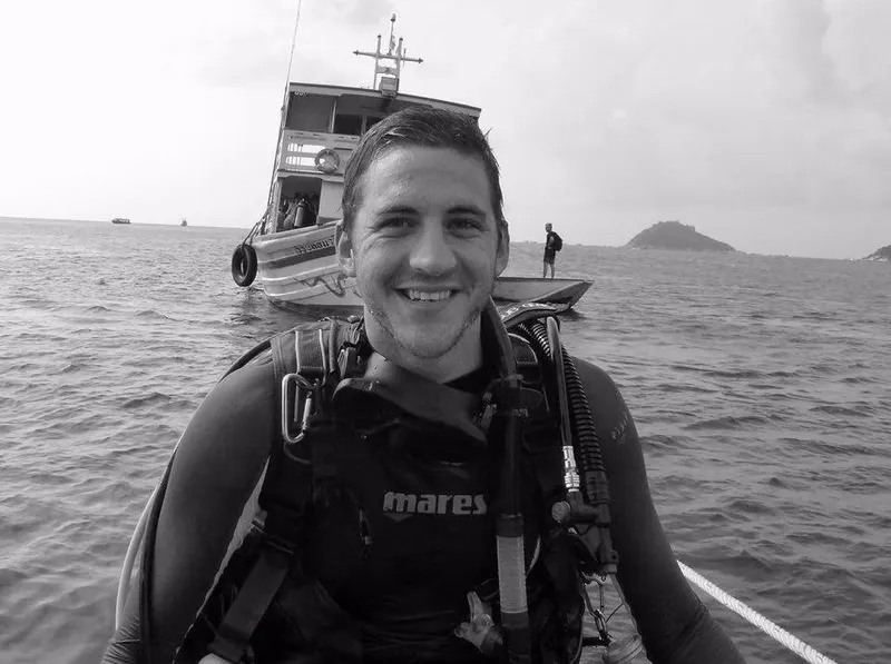 Plongeur souriant en équipement complet, bateau de plongée en arrière-plan