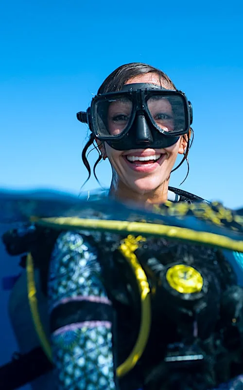 Plongeuse souriante avec masque et combinaison, prête pour l'aventure aquatique