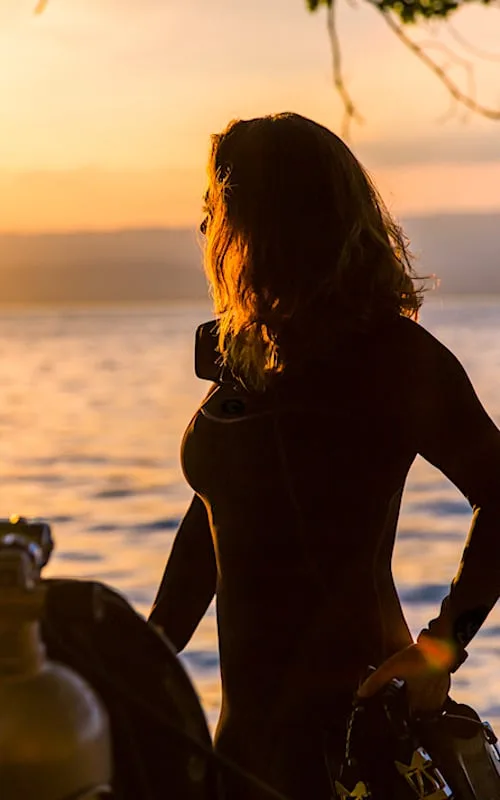 Plongeuse en silhouette, préparant son équipement au coucher du soleil