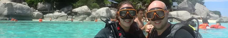 Deux plongeurs souriants avec leur équipement sur une plage paradisiaque