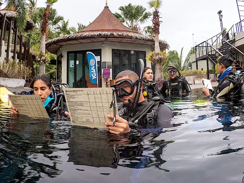 Plongée : des participants étudient des documents dans une piscine