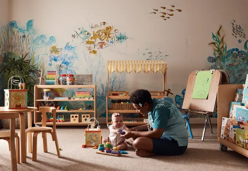 Une femme et un bébé jouent avec des jouets dans une pièce décorée