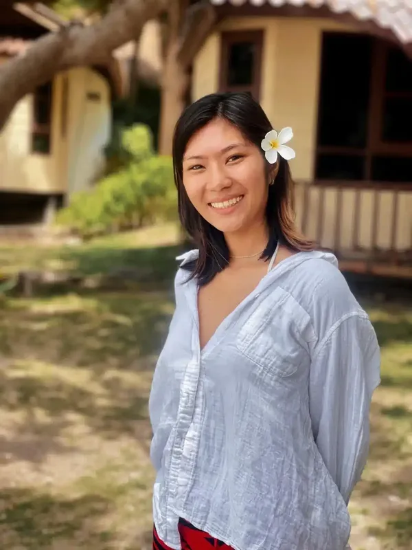 Jeune femme souriante avec une fleur dans les cheveux devant un bâtiment