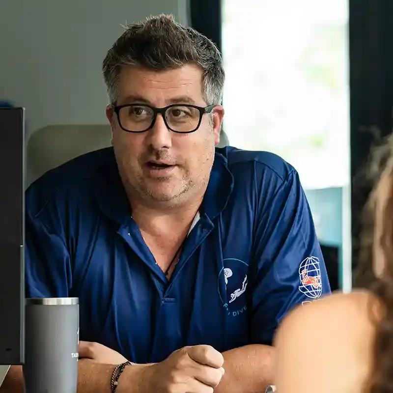 Homme portant des lunettes et un polo bleu, regardant vers la gauche