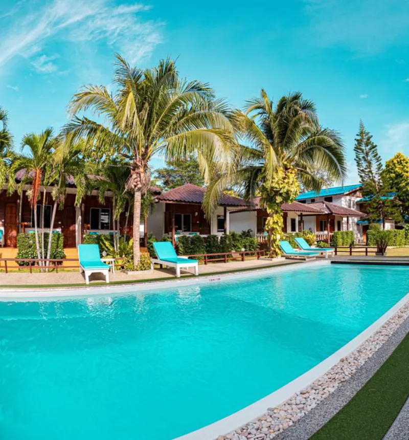 Piscine turquoise bordée de transats et de végétation tropicale luxuriante