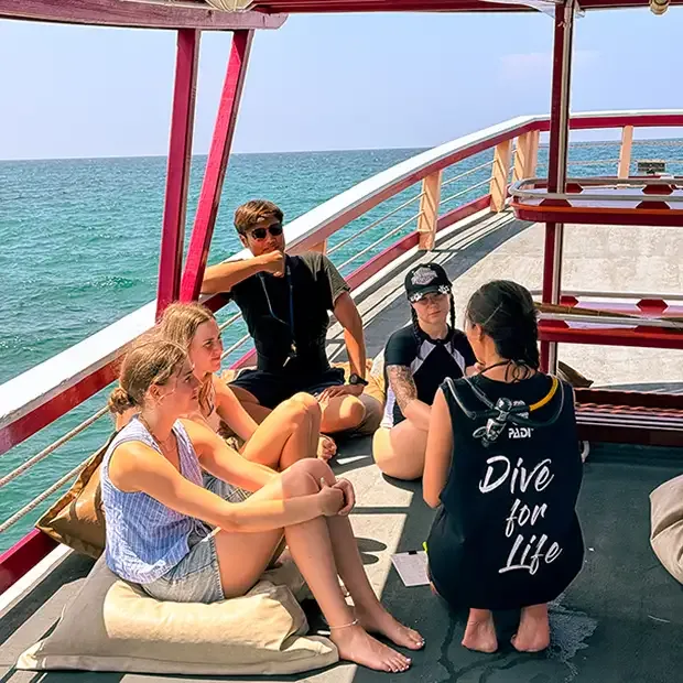 Quatre personnes assises sur un bateau de plongée en mer