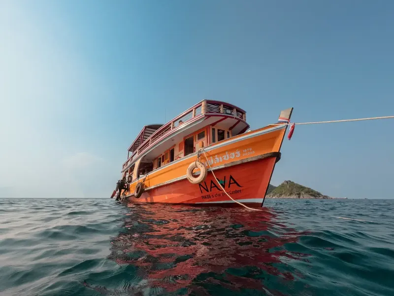 Bateau orange et blanc sur une mer calme avec une île