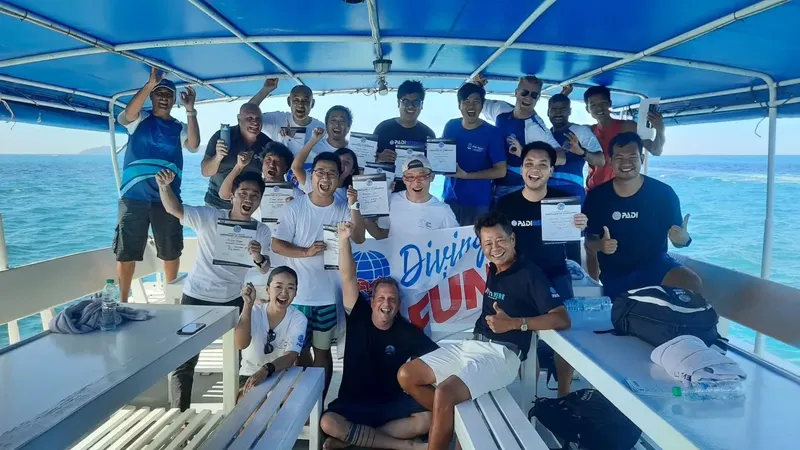 Groupe de plongeurs souriants sur un bateau en mer, célébration