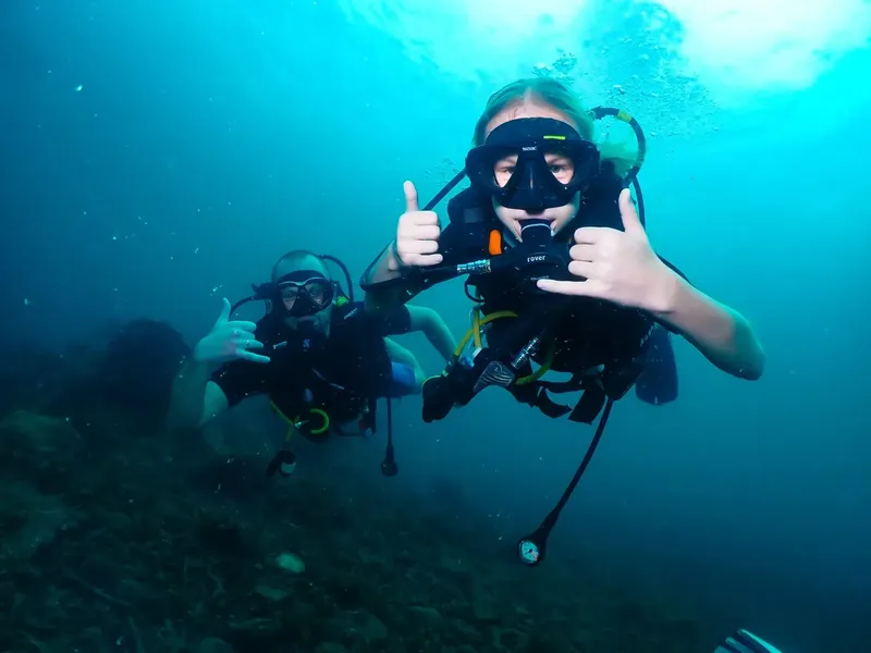 Deux plongeurs souriants font un signe de validation sous l'eau