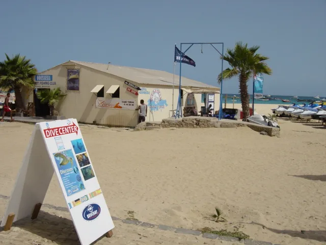 Centre de plongée sur une plage de sable avec bateau et panneaux