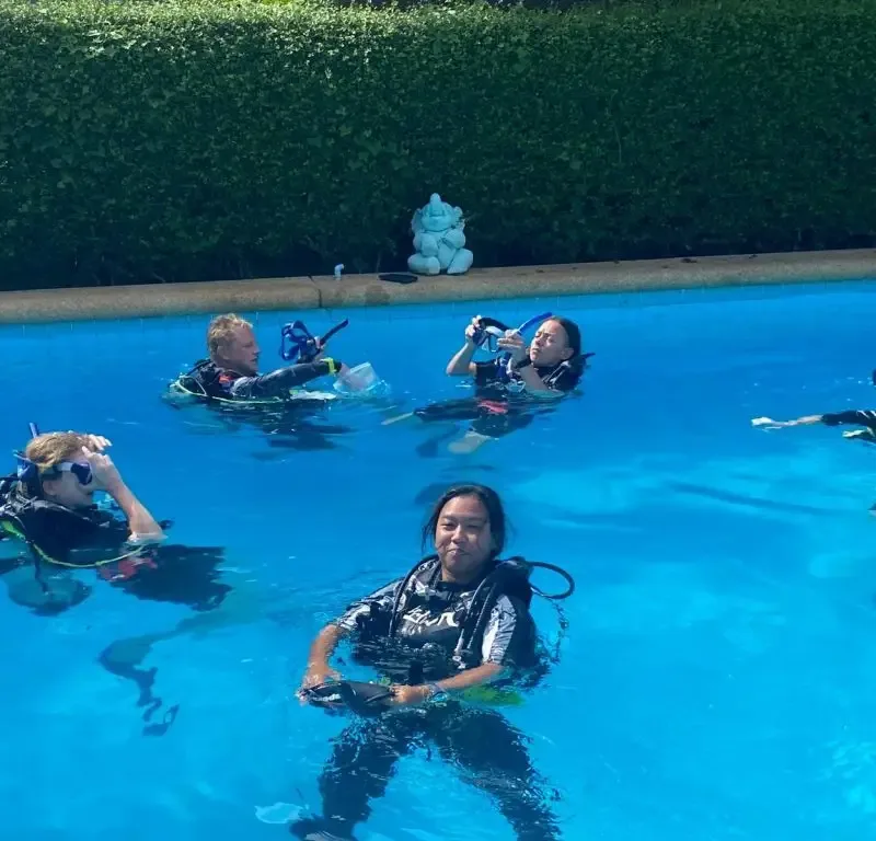 Quatre plongeurs en formation dans une piscine, équipement complet visible
