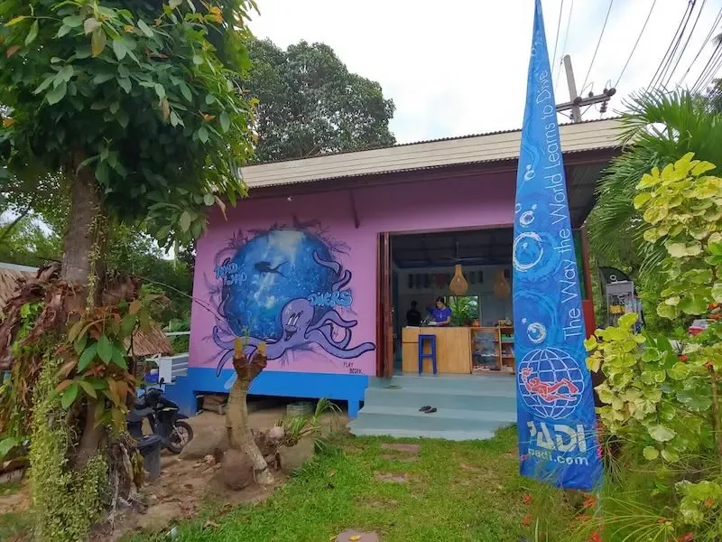 Façade d'un centre de plongée avec une fresque marine et un drapeau PADI