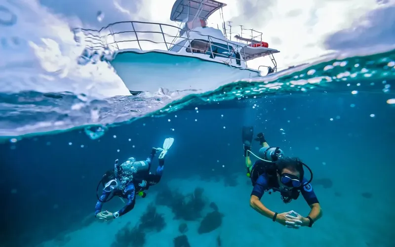 Deux plongeurs explorent les fonds marins sous un bateau de plongée
