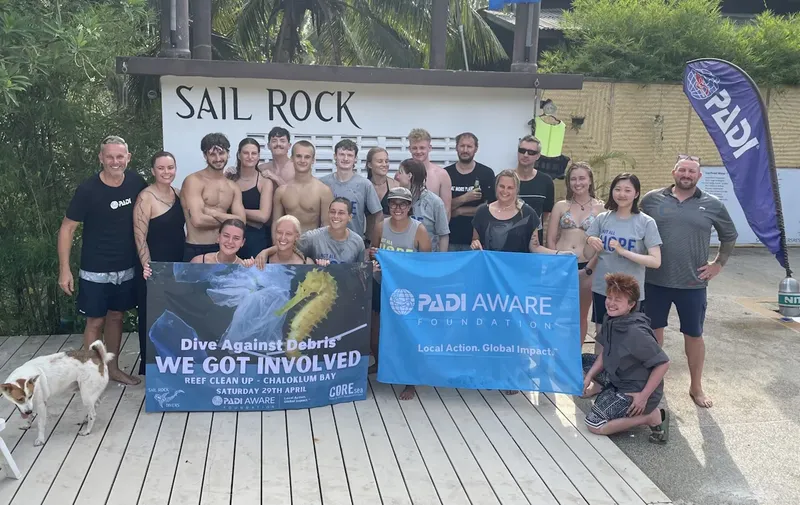 Groupe de personnes souriantes posant avec une bannière de sensibilisation