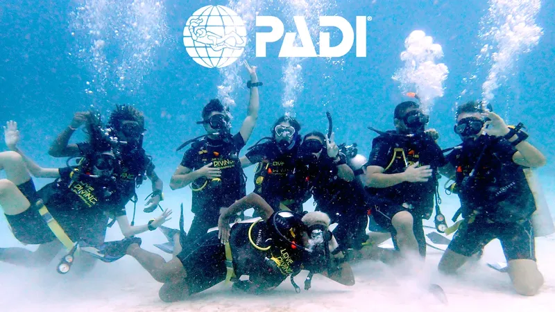 Groupe de plongeurs souriants avec le logo PADI en surface