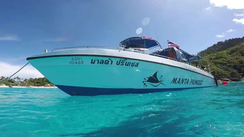 Bateau de plongée turquoise en mer, personnes à bord, ciel bleu clair