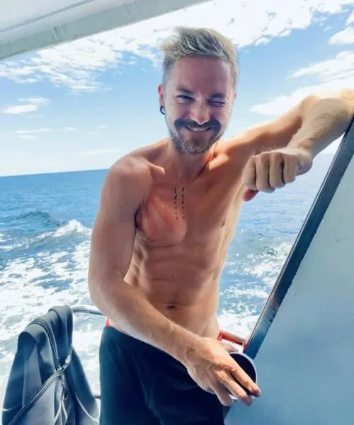 Homme souriant torse nu sur un bateau en mer