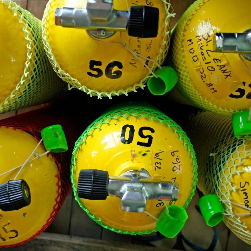 Bouteilles de plongée jaunes empilées avec détendeurs et manomètres verts