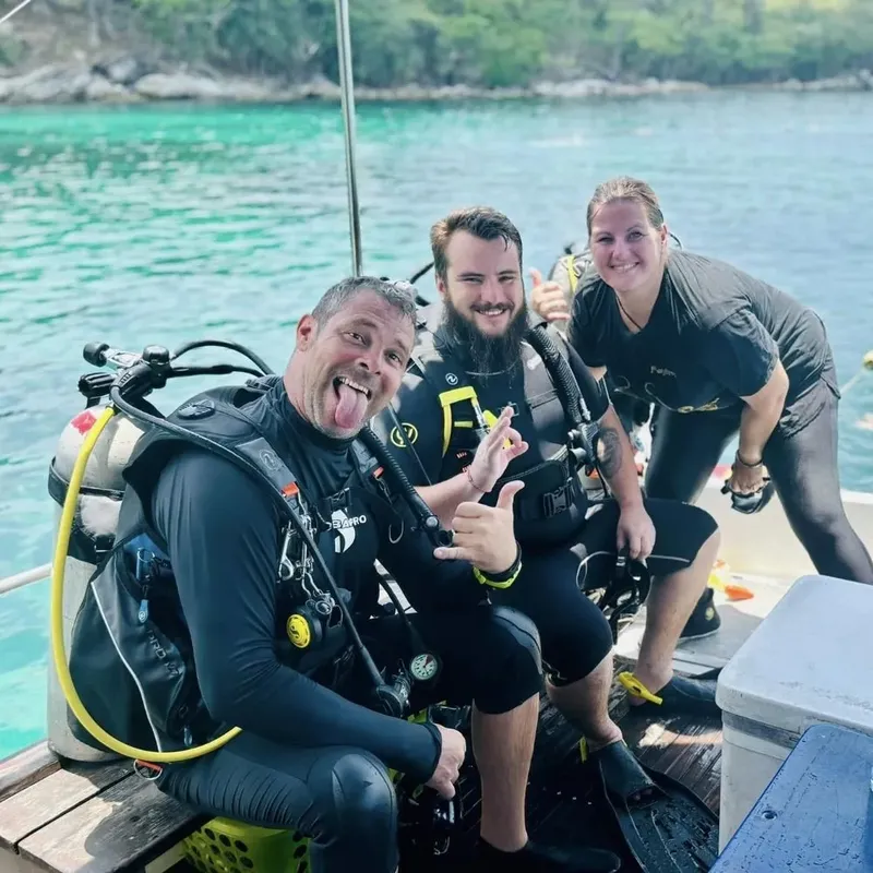 Trois plongeurs souriants sur un bateau après une immersion
