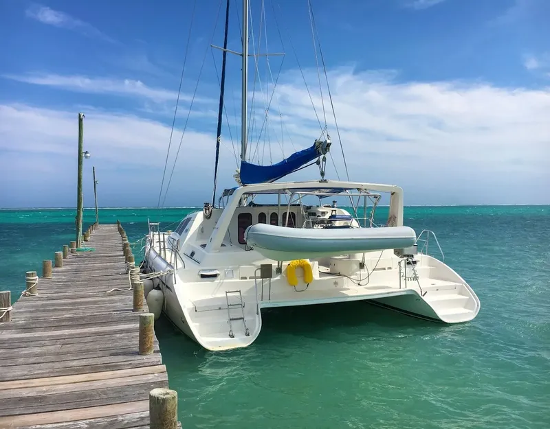 Catamaran amarré à un ponton en bois sur une eau turquoise