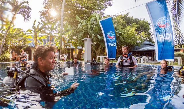 Instructeur de plongée explique les consignes à des élèves en piscine