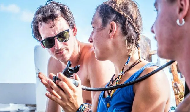 Trois plongeurs discutent du matériel de plongée sur un bateau