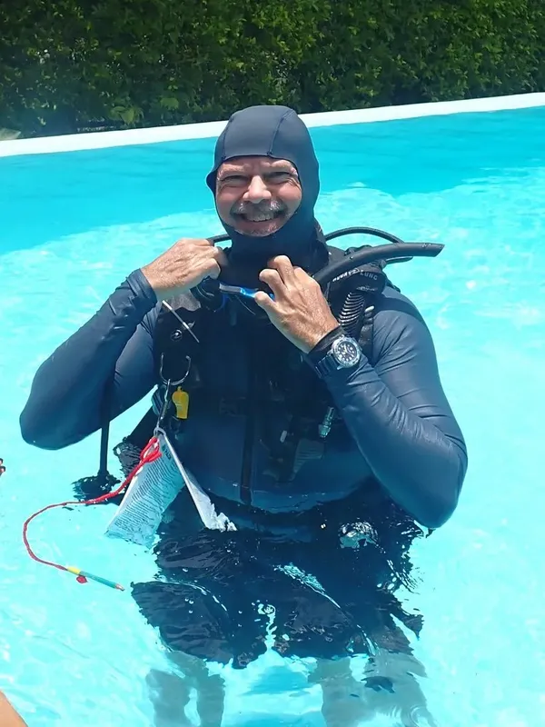 Plongeur en combinaison s'equipant dans une piscine bleu clair