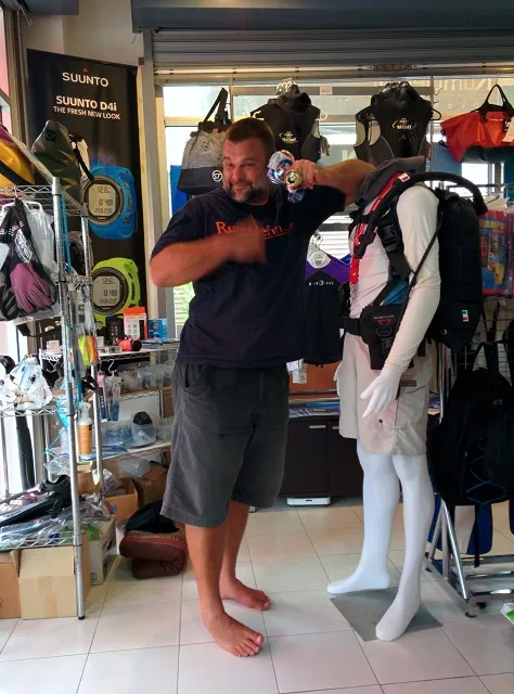 Un homme ajuste un gilet de plongée sur un mannequin dans un magasin