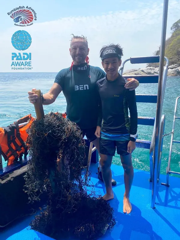Deux plongeurs souriants sur un bateau bleu en mer