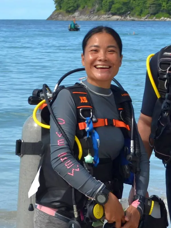 Plongeuse souriante avec son équipement sur une plage ensoleillée