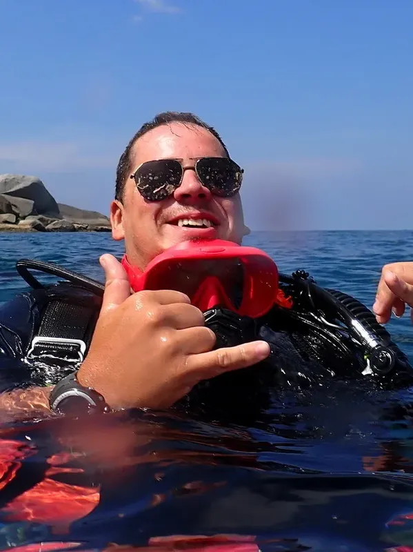 Plongeur souriant avec lunettes de soleil et signe de la main