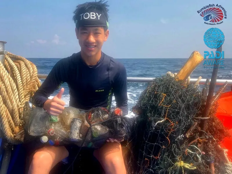 Jeune homme souriant sur un bateau avec des filets de pêche
