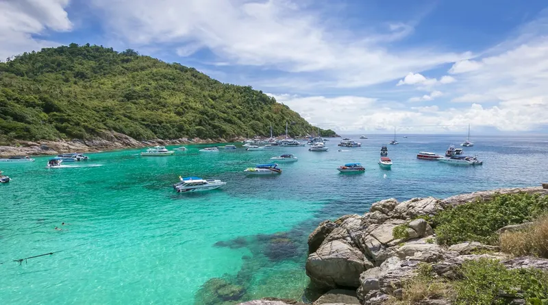Anse turquoise avec bateaux de plaisance et quelques personnes dans l'eau