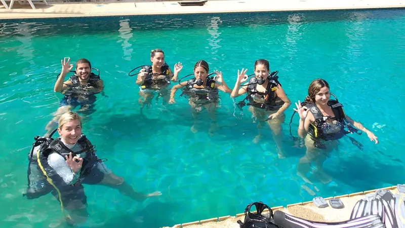 Groupe de plongeurs souriants en formation dans une piscine ensoleillée