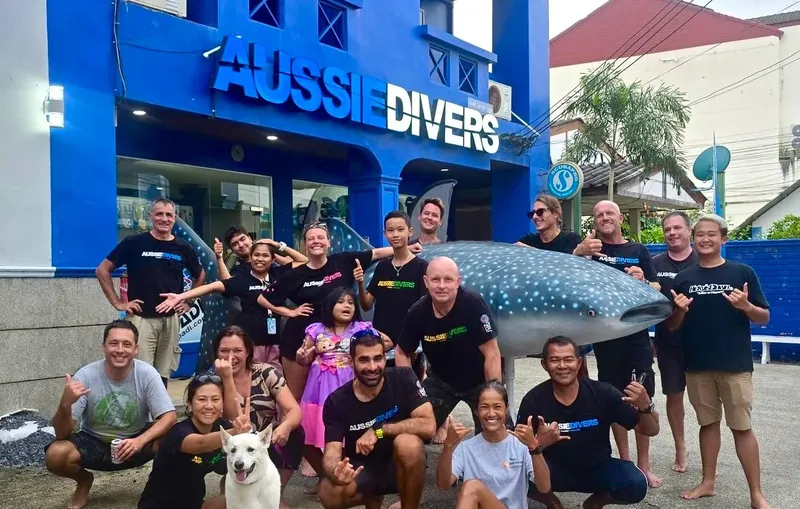 Groupe de personnes posant avec une statue de requin baleine devant un centre