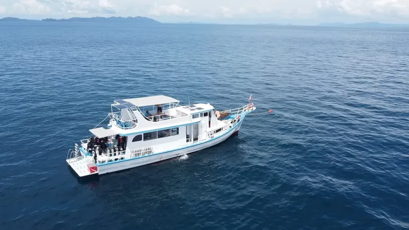 Bateau de plongée blanc avec des plongeurs préparant une sortie en mer