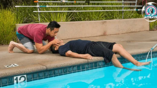 Un homme prodigue les premiers secours à une personne allongée près d'une piscine