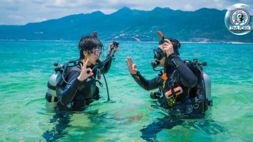 Deux plongeurs équipés dans l'eau turquoise, vérifiant leur matériel