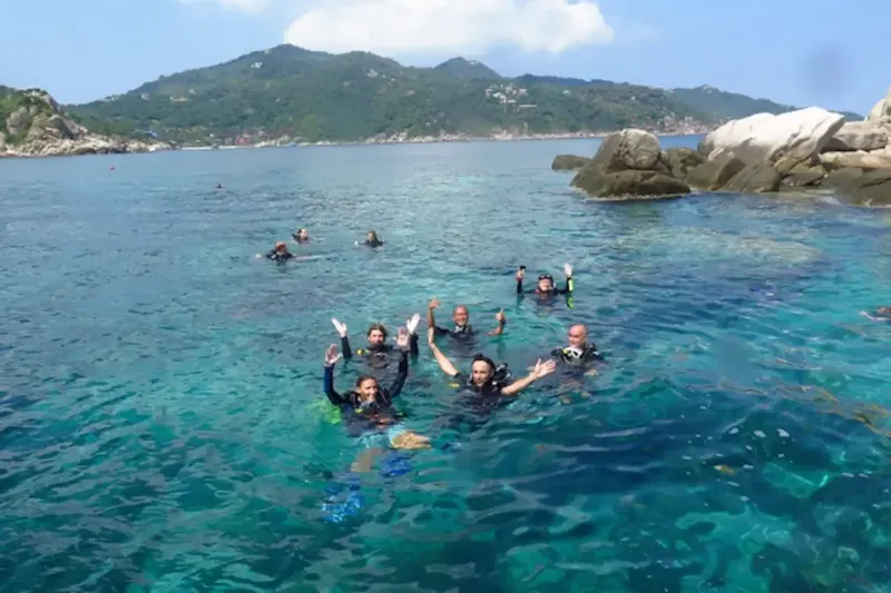 Groupe de plongeurs souriants dans une eau turquoise claire