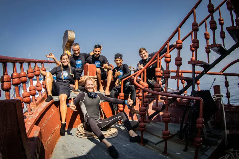 Groupe de plongeurs souriants sur le pont d'un bateau en mer