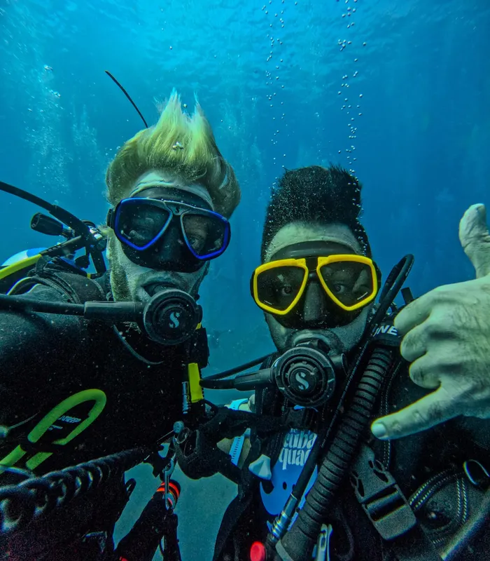 Deux plongeurs souriants avec leur équipement sous-marin dans l'eau bleue