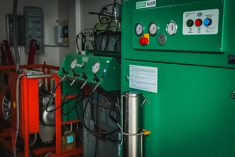 Compresseur de plongée industriel vert et orange avec manomètres et tuyaux