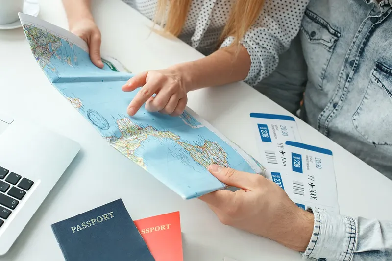 Deux personnes examinent une carte et des billets d'avion sur une table