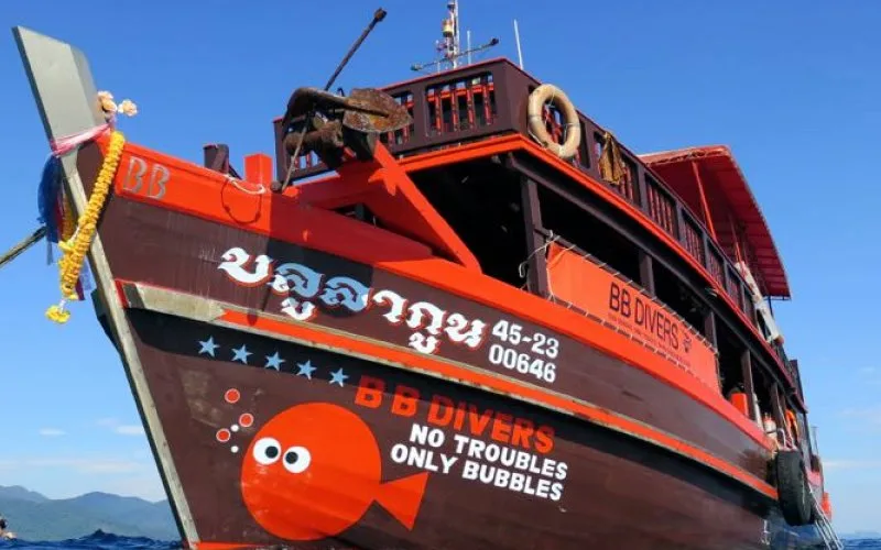 Bateau de plongée rouge avec logo et inscription en langue étrangère