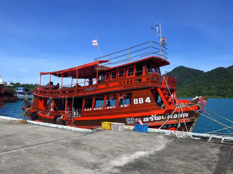 Bateau rouge amarré à un quai avec des passagers à bord
