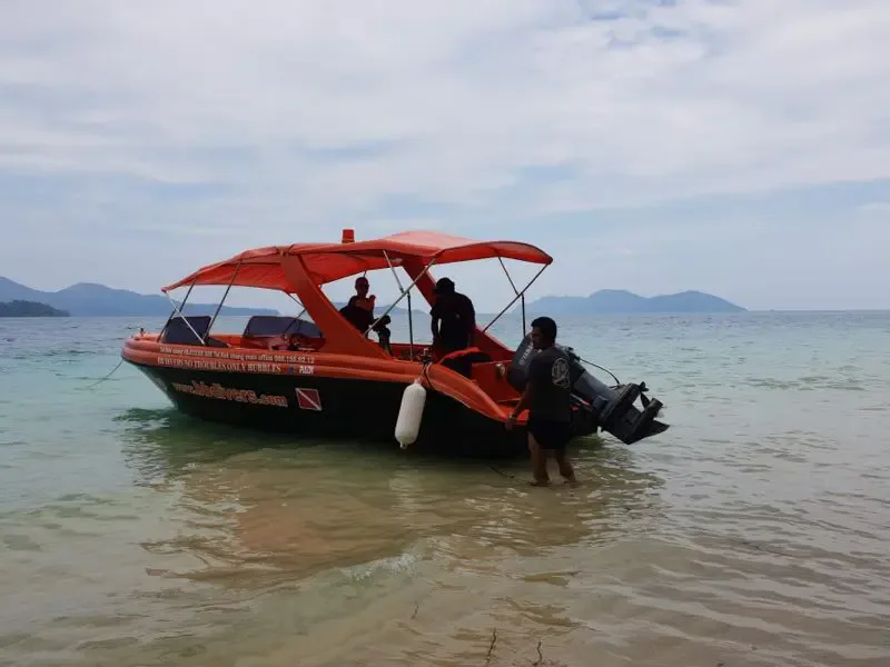 Bateau orange avec des plongeurs à bord sur une mer calme